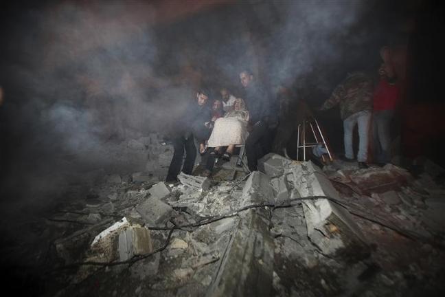 Palestinians help to evacuate a woman following Israeli air strikes in Gaza City, November 14, 2012. CREDIT: REUTERS/ALI HASSAN