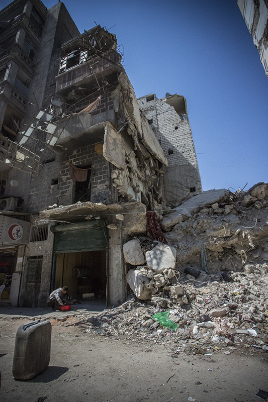 Aleppo, Syria - 2013. A building destroyed by repeated shelling, residents have tried to keep their business on the ground floor running. © Hannah Lucinda Smith