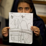 Nabila Rehman, 9, holds up a picture she drew depicting the U.S. drone strike on her Pakistan village which killed her grandmother Mammana Bibi, at a news conference on Capitol Hill in Washington October 29, 2013. Nabila and her father and brother attended the news conference on Monday to highlight the personal costs in collateral damage for civilians killed and injured in the U.S. drone strike program. REUTERS/Jason Reed (UNITED STATES - Tags: POLITICS MILITARY TPX IMAGES OF THE DAY) - GM1E9AU04C601