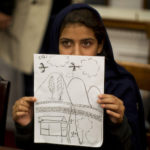 Nabila Rehman, 9, holds up a picture she drew depicting the U.S. drone strike on her Pakistan village which killed her grandmother Mammana Bibi, at a news conference on Capitol Hill in Washington October 29, 2013. Nabila and her father and brother attended the news conference on Monday to highlight the personal costs in collateral damage for civilians killed and injured in the U.S. drone strike program. REUTERS/Jason Reed (UNITED STATES - Tags: POLITICS MILITARY TPX IMAGES OF THE DAY) - GM1E9AU04C601