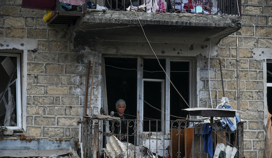 A woman looks out of her apartment window in the aftermath of recent shelling during a military conflict over the breakaway region of Nagorno-Karabakh in Stepanakert